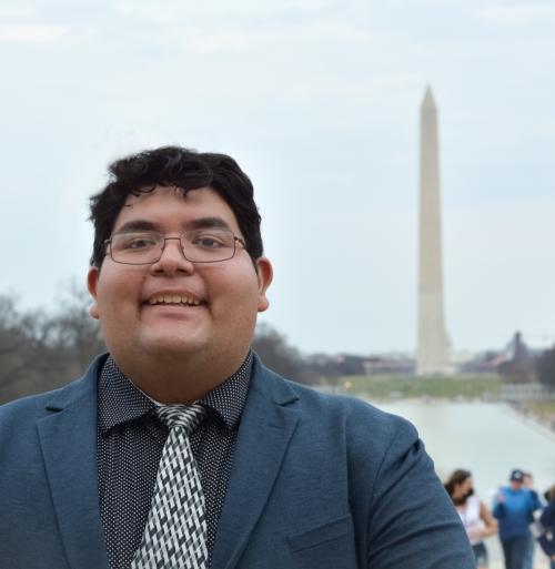 David Mesta in suit and tie posing in front of Washington Monument