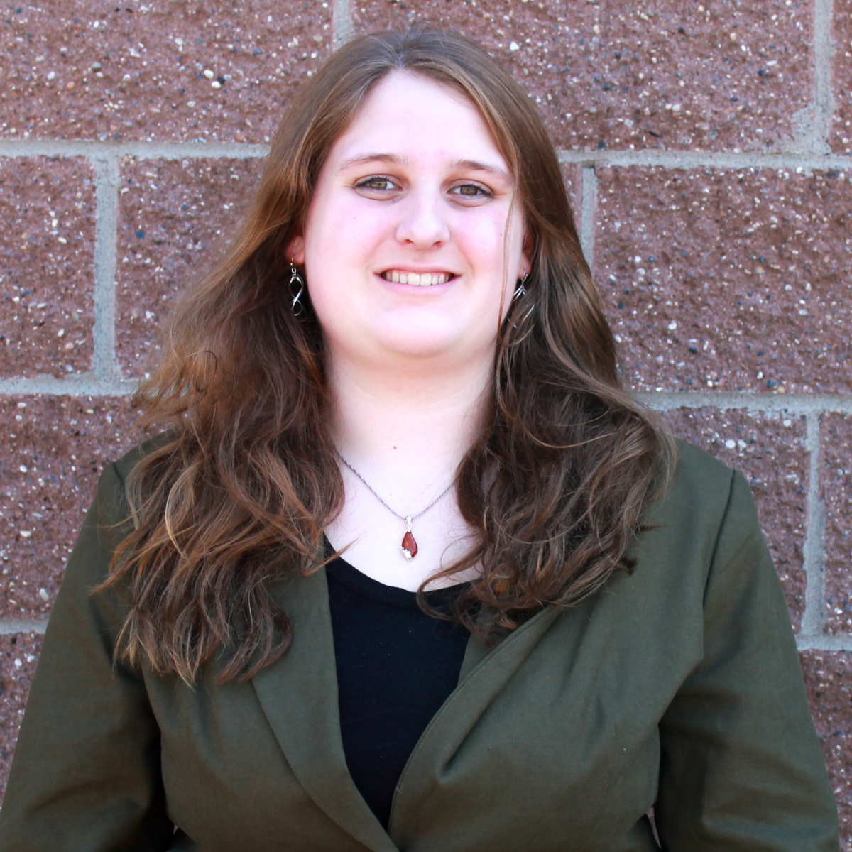 photo of olivia small, video production associate against red/copper brick